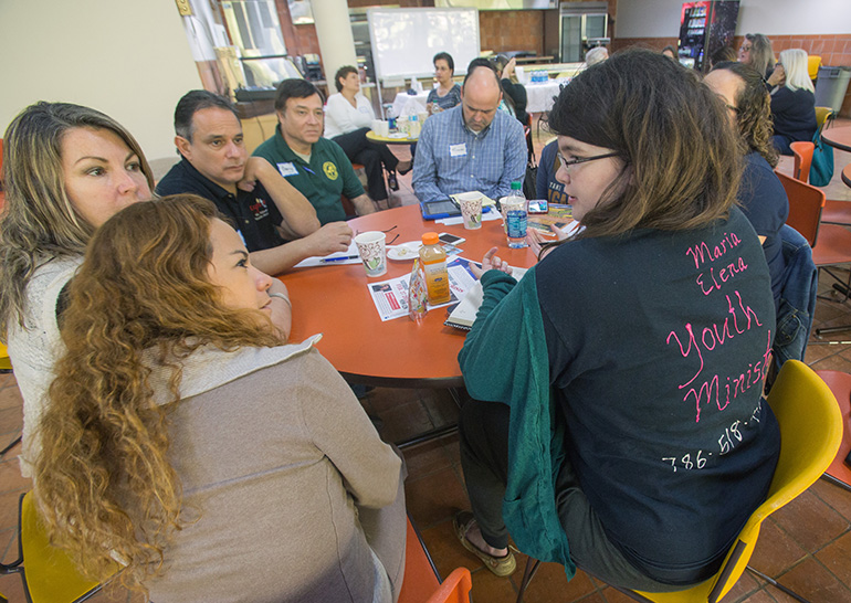 Maria Elena Murdoch, right, director of Youth and Young Adult Ministry at Our Lady of Lourdes Church in Miami, talks to Siulin Kang, from Little Flower Church, Coral Gables, as others at the table listen.