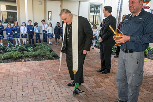 Archbishop Thomas Wenski shows students his alligator socks as St. Anthony's maintenance director, Andy Massagee, looks on.