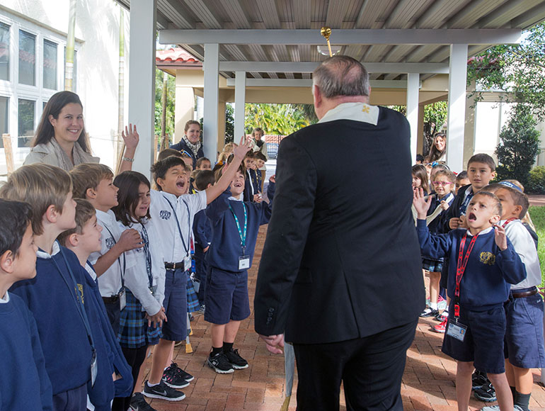 St. Anthony second grader, Dylan Matthews, 8, at left, and first grader, Giovanni Serra, 7, at right, react to receiving a holy water blessing from Archbishop Thomas Wenski.