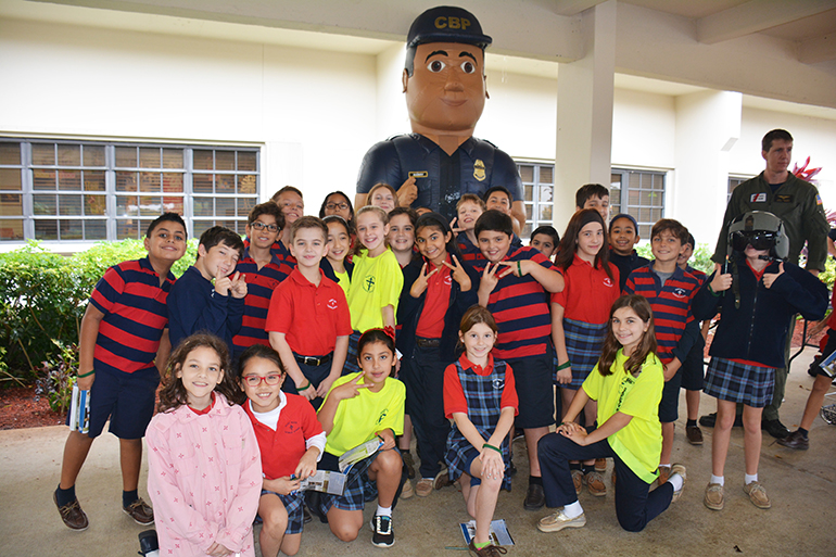St. Mark students pose with a really big law enforcement officer, played by a costume-wearing eighth-grader Ian Lynch.