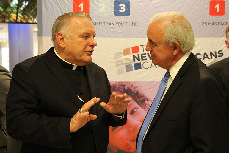 Archbishop Thomas Wenski gets in a few words with Miami-Dade County Mayor Carlos Gimenez during the press conference for the New Americans Campaign launch of Citizenship 1-2-3 in February 2016. Catholic Legal Services of the Archdiocese of Miami has been helping legal immigrants fill out citizenship applications as part of the campaign but the final step for hundreds of thousands - taking the oath of citizenship - has been put on hold by the coronavirus pandemic.