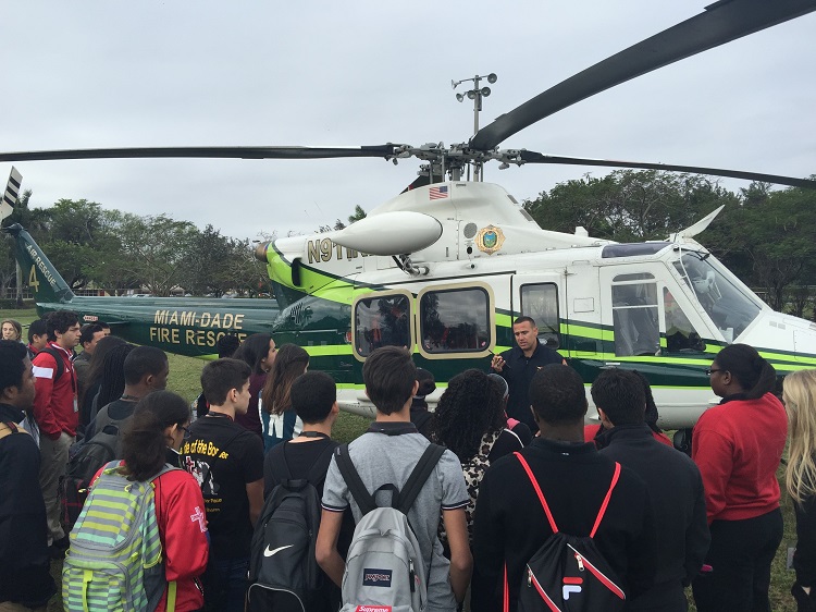 Lt. Alex Acosta, a flight medic with Miami-Dade Fire Rescue, speaks with a group of Pace students in front of a fire rescue helicopter as part of Msgr. Edward Pace High School's annual Career Day.