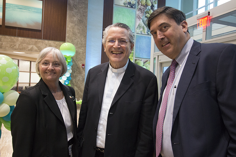 La Hna. Stephanie Flynn, una de las tres Hermanas de San José de San Agustín, miembro del consejo administrativo del Hospital Mercy, posa con Mons. Gabriel Ghanoum, coordinador de atención espiritual de la División Este de la Florida de HCA, (al centro), y Michael Joseph, presidente de la División Este de la Florida de HCA. Se bendijo y se inauguró el renovado vestíbulo del Hospital Mercy , parte de una renovación de más de $ 120 millones de dólares que incluye una nueva sala de meditación, ventanas a prueba de impactos, y habitaciones privadas para los pacientes en todos los ocho pisos del hospital.  El hospital Mercy es propiedad y está operado por HCA, pero sigue siendo patrocinado por las Hermanas de San José de San Agustín.