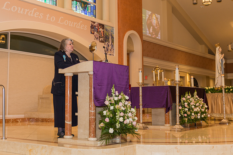 Marlene Watkins, president of the North American Volunteers, guides the Miami pilgrims through the Lourdes Experience.