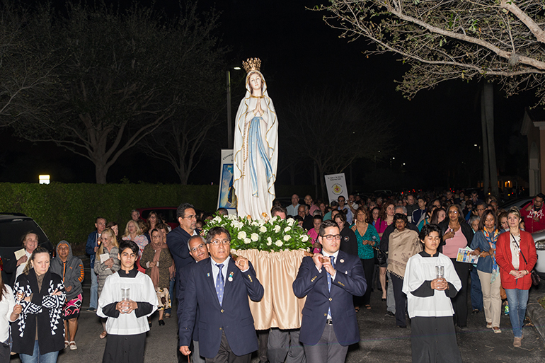 Volunteers of Our Lady of Lourdes and virtual pilgrims pray the rosary in the candlelight procession.
