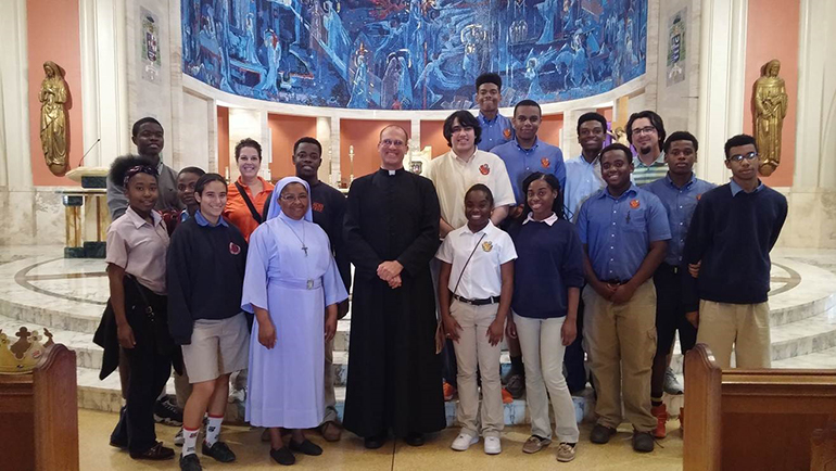 Pilgrims from Archbishop Curley Notre Dame pose with Father Christopher Marino, rector, at St. Mary Cathedral.