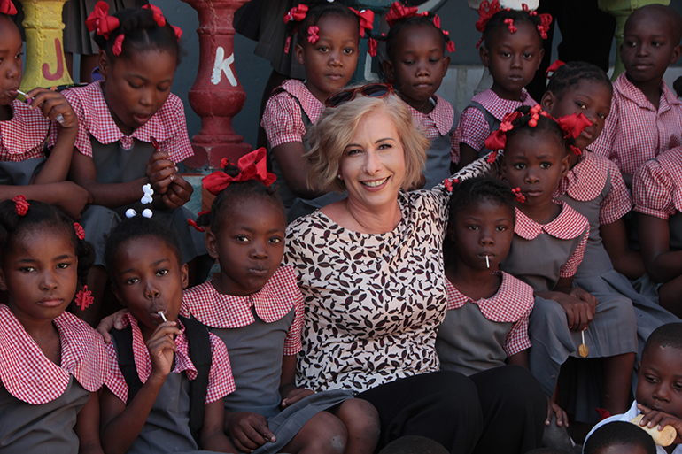 Ana Garcia poses for a photo with the children of Nan Palan, sister school for Our Lady of the Lakes in Miami Lakes.