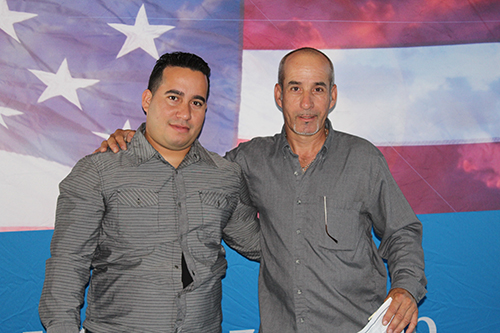 Loandres Fernandez, left, and Rodolfo Blanco take a quick photo in front of their adoptive flag before the start of their naturalization ceremony at Marlins Park March 19.