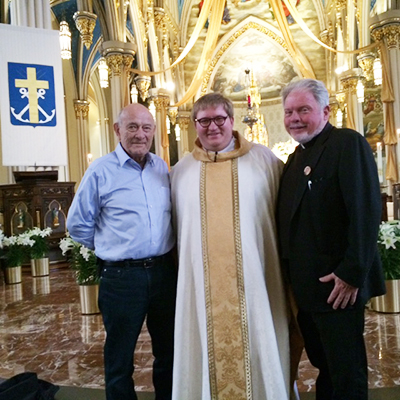 Deacon Bob Binder, left, and Father Curtis Kiddy stand with the newly-ordained Holy Cross Father Matthew Hovde after he preached his first Mass April 3 at the Basilica of the Sacred Heart.