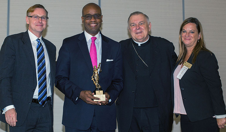 Posing, from left: Randolph McGrorty, Catholic Legal Services CEO; New American Pro Bono recipient Marlon Hill; Archbishop Thomas Wenski; and outgoing CLS board president Mary Kramer.