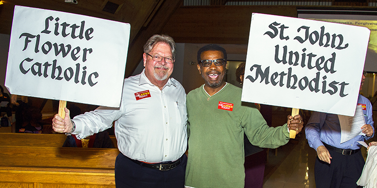 From left, Hara E. Ahrens of Little Flower Church in Hollywood and Sam Battle of St. John United Methodist Church hold up their signs.