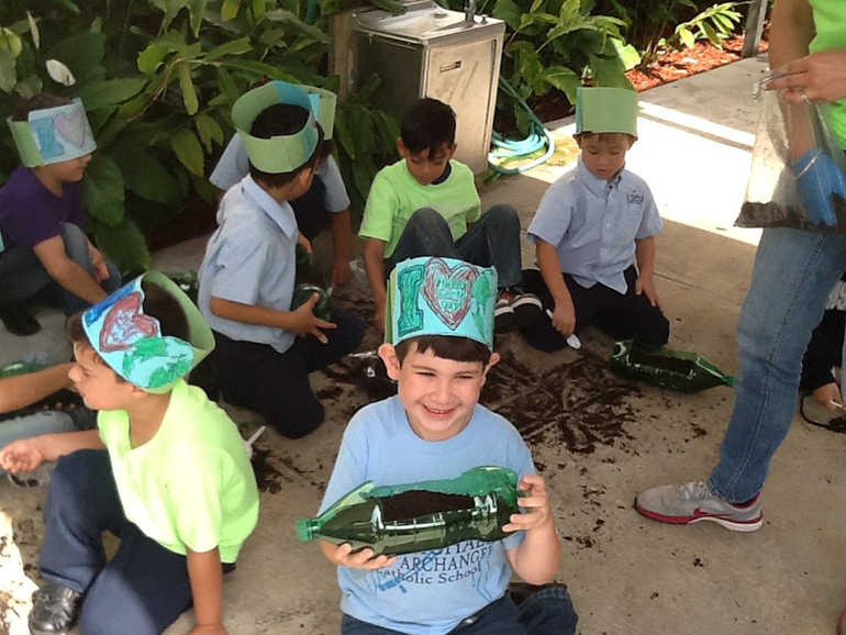 Kindergartener Miguel Rojas shows off his eco-friendly terrarium as his classmates work behind him.