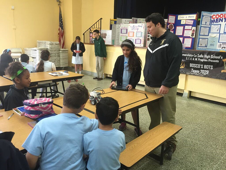 Nick Suarez, of Immaculata-La Salle High School’s robotics team, demonstrates one of their robots for a student at St. Michael School.