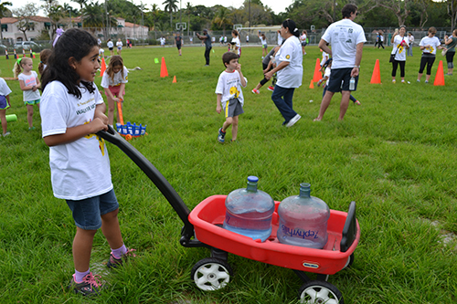 St. Theresa first grader Sofia Castillo hauls large water bottles through the obstacle course at the Walk for Water fundraising event.