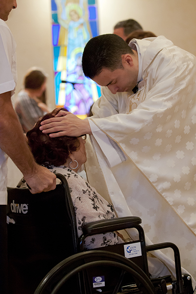 Father Jose Alfaro prays over Dolores Pupo during the Healing Mass May 6, part of Blessed Trinity's Easter Mission.