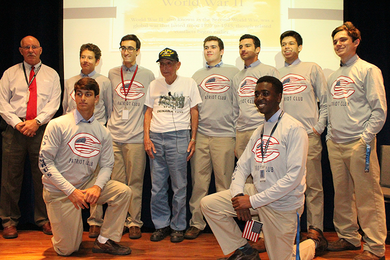 Members of Christopher Columbus High School's Patriot Club pose with World War II Todd Silverman (center) after his presentation. The club is moderated by guidance counselor Carter Burrus (far left), who served in the U.S. armed forces.