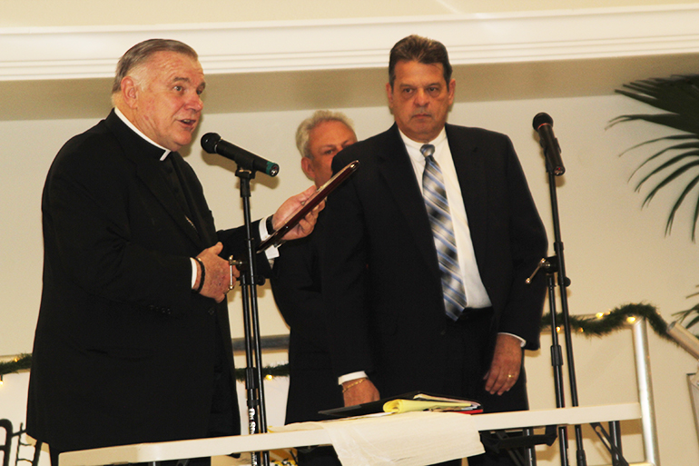 Archbishop Thomas Wenski gives an award of appreciation to Dr. Edward Suarez, one of the medical professionals who volunteers his time and talent at the St. John Bosco Clinic in Miami.