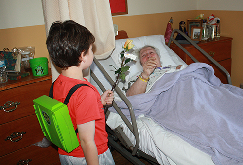 Six-year old Ian Devoto hands a rose to Waterford Nursing home resident Angela Ortiz, who showed her appreciation by saying, "God bless you!"