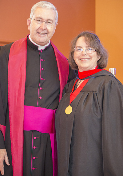 Msgr. Terence Hogan, dean of St. Thomas University's School of Theology and Ministry, poses with Minette Sternke, who received a master in pastoral ministries with specialization in deaf ministry. Sternke lost her hearing at the age of 14 but obtained bachelor's and master's degrees in accounting and banking and has worked for the FDIC for 27 years. She also is a devout Catholic who has served her parish as deaf minister coordinator since 1999. In 2015, she became a consecrated virgin.