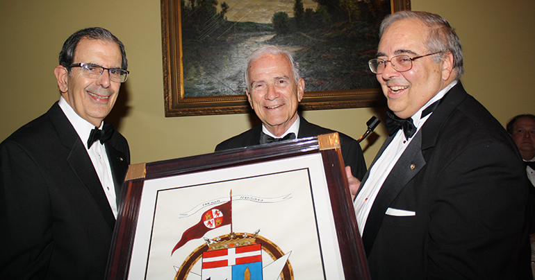 Juan Jose Calvo, left, president of the Cuban Association of the Order of Malta, and Juan O'Naghten, right, vice-president, present a tribute to President Emeritus Fernando Garcia-Chacon.