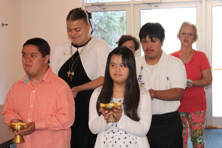 Los estudiantes y voluntarios del Centro Mariano llevan el ofertorio durante la Misa: En la primera fila, desde la izquierda, John Vanegas y Jacqueline Liu; fila del medio, izquierda, Michaela Adler y Leonardo Orozco; última fila, Shirley Moye y Rita Chiofalo, ambas presentaron sus peticiones para unirse a la Asociación de Agregados Laicos de las Hermanas de San José Benito Cottolengo.