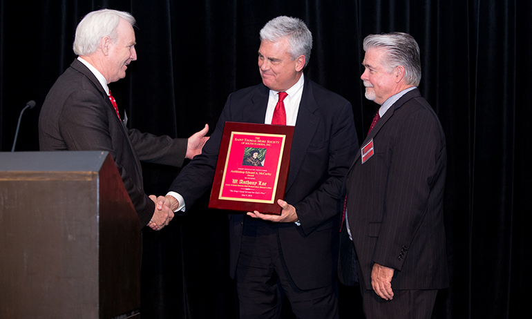 Robert M. Bulfin, left, president of the St. Thomas More Society of South Florida, presents the society's annual award to attorney Anthony "Tony" Loe, a prosecutor for the Broward County State Attorney's Office in Fort Lauderdale.  At right is Judge Dennis Bailey.