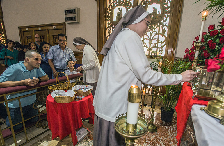 Sister Josephine Lundstrom, of the Servants of the Pierced Hearts, touches a religious item to the relic of St. Thomas More as Sister Grace Hienrich hands St. Thomas More and St. John Fisher holy cards to those in line.