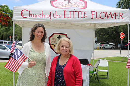 Cristina Sousa, left, and Maria Wadsworth, of Little Flower's Catholic Disciples in the Public Square, pose in front of their display table after the Mass celebrated by Archbishop Thomas Wenski.