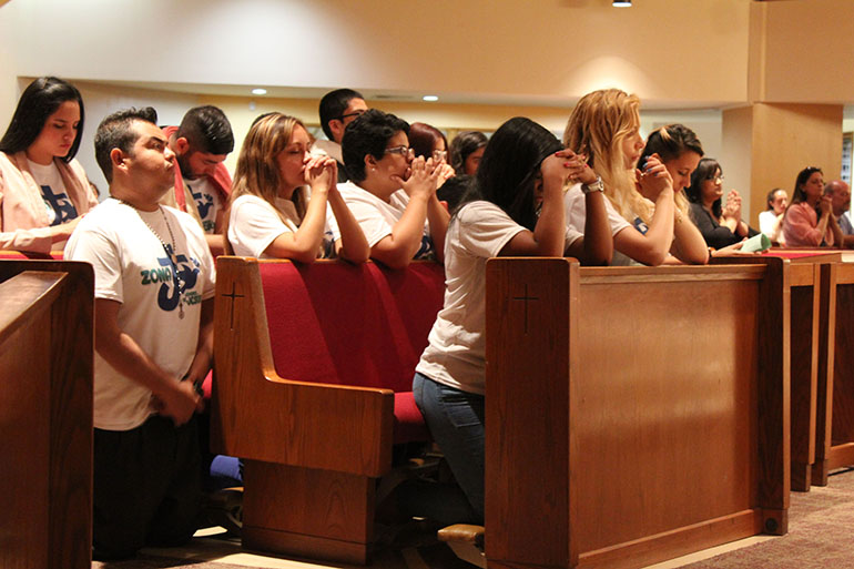 Members of St. Boniface’s young adult group kneel during the Mass celebrated by Archbishop Thomas Wenski. They were recognized for being the largest group at Illuminare La Notte's first anniversary, and first neighborhood edition, June 24.