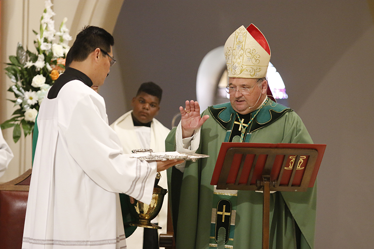 Bishop Peter Baldacchino blesses the pilgrim crosses he and other priests would give to World Youth Day pilgrims at the end of the send-off Mass.