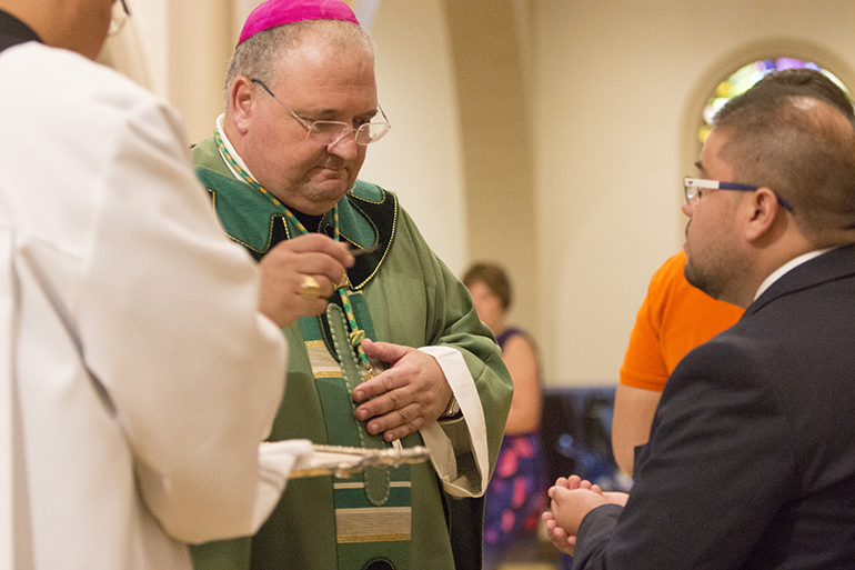 Bishop Peter Baldacchino distributes pilgrim crosses to World Youth Day pilgrims from throughout the Archdiocese of Miami.