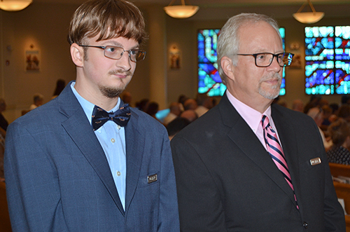 Gabriel Grove volunteers as an usher during Sunday Mass at St. Bonaventure Church, assisted by his father, Gary.