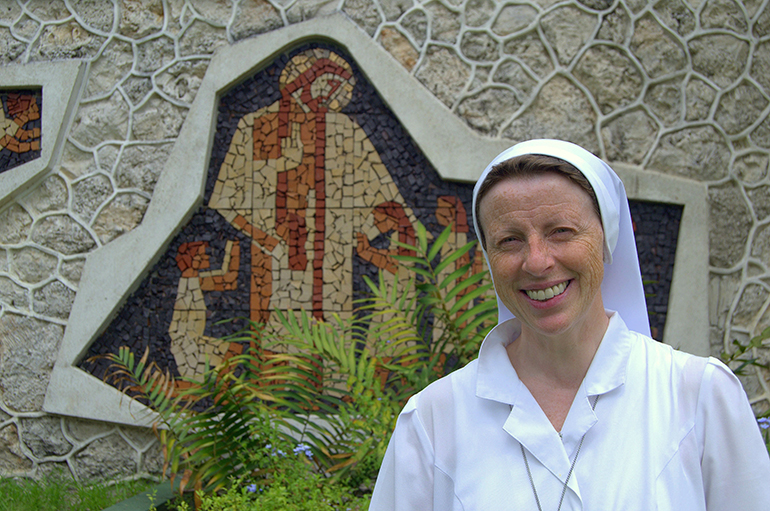 Sister Lidia Valli, executive director of the Marian Center, pauses in front of a mosaic of Jesus and children.