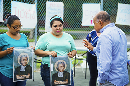 El nuevo administrador de la Misión Santa Ana, el P. Rafael Cos bendice las imágenes de San Juan Bautista de La Salle, durante una reunión por el 25 aniversario del Centro de Artes y Oficios de La Salle, en Homestead. Atrás, desde la izquierda, las profesoras del centro Andrea Morales y Karen Morales.