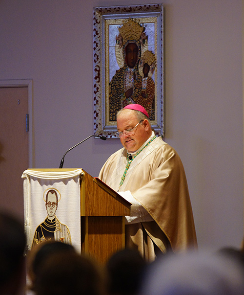 Miami Auxiliary Bishop Peter Baldacchino delivers his homily at St. Maxiimilian Kolbe Parish in Pembroke Pines on the 75th anniversary of the saint's death in Auschwitz. The icon of Poland's Black Madonna, Our Lady of Czestochowa, is behind him.