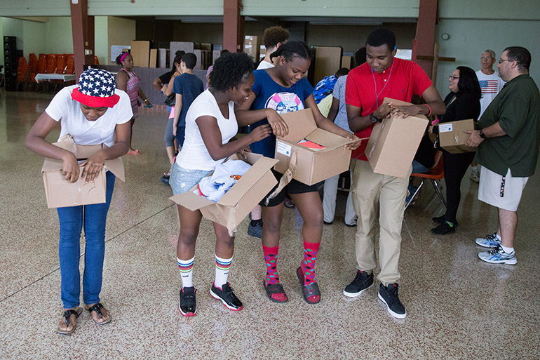 Students at Archbishop Curley Notre Dame Prep in Miami open up their uniform gift boxes after receiving them Aug. 16.