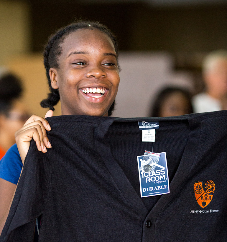 A student at Archbishop Curley Notre Dame Prep holds up one item of a donated school uniform Aug. 16. Money from the archdiocese's 55th anniversary gala in October 2013 provided the funds for the clothing.