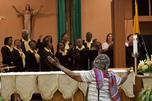 Melizanne Marcellus, a parishioner at St. Stephen in Miramar, dances during the closing hymn performed in Creole at her parish's 60th anniversary Mass.