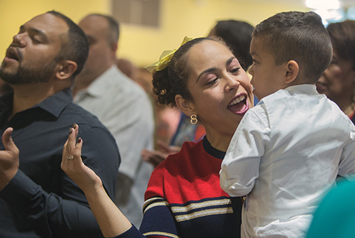 Alejandra Martinez sings during Mass while holding her son, Frankie Martinez, 3. Her husband, Francisco Martinez, is at left.
