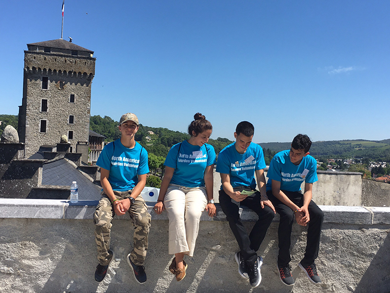 While sightseeing in France, Jose Sanchez (center right) and his brother Jean (right) take a break with two other North American Lourdes Volunteers. Jose and Jean came with a group consisting of students from Coleman Carroll High and the young adult group from Our Lady of Lourdes Parish in Miami.