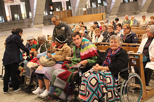 Pilgrims await the start of Mass at the Basilica of St. Pious X, also known informally as the Underground Basilica, found on the ground of the Sanctuary of Our Lady of Lourdes.