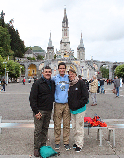 Archbishop Coleman Carroll High sophomore Anthony Valenzuela poses with his parents in front of the Basilica of Our Lady of the Rosary. Anthony and his family were a part of the North American Lourdes Volunteers who came to aid sick pilgrims on pilgrimage to Our Lady of Lourdes, France.