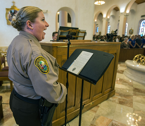 Officer Bridget Sanchez, Miami-Dade Police Dept., sings "America the Beautiful" at the annual Blue Mass for law enforcement officers.