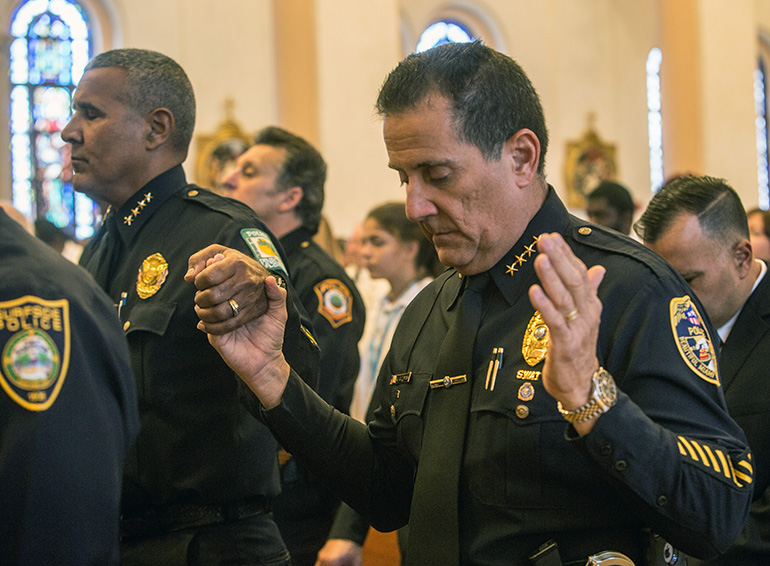 Armando Guzman, right, Miami Springs Police Dept., and Pinecrest Police Chief Samuel Ceballos, Jr. hold hands while saying "The Lord's Prayer."