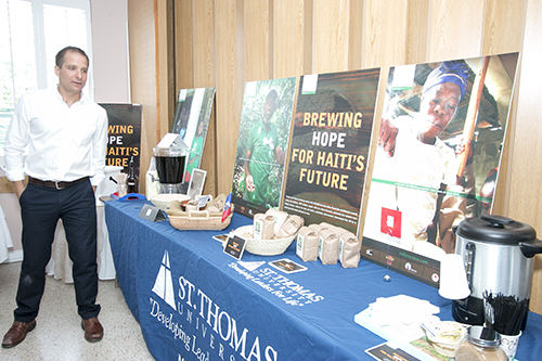 Anthony Vinciguerra, director of St. Thomas University's Center for Community Engagement, poses in front of the Cafe Cocano display at the reception that followed the Mass marking the 40th anniversary of Amor en Accion. Amor en Accion partnered with the university to help the coffee-growing farmers in the region get their coffee to market in Florida.