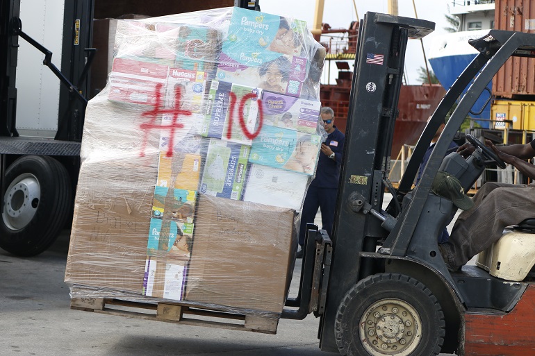 Los trabajadores de Seacoast Shipping meten un pallet con pañales dentro del carguero Betty K VI, atracado en el río de Miami, el 14 de octubre.