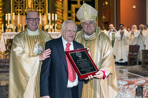 Father Michael Davis, Little Flower's pastor, and Archbishop Thomas Wenski present a plaque to Ed Brownell, a member of St. Theresa School's (then St. Joseph's Academy) first graduating class.