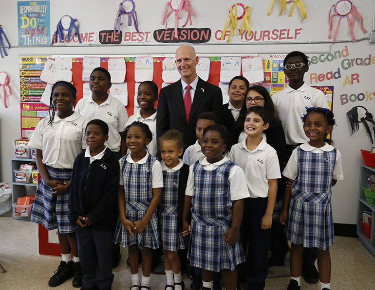 Fla. Gov. Rick Scott poses with students from grades one through eight during an Oct. 21 visit to St. Mary Cathedral School. Gov. Scott stopped in a classroom before meeting at the school with local officials concerning a new outbreak of Zika cases in the Little River area, where the cathedral is located.