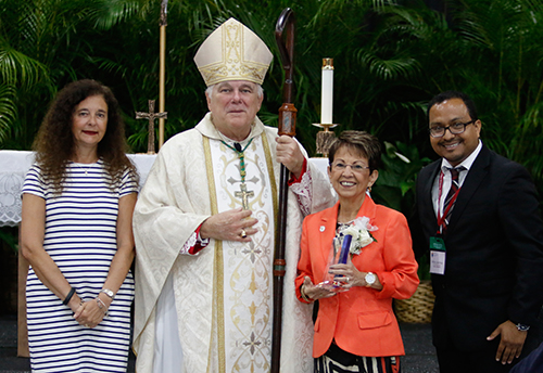 Accompanied by Superintendent of Schools Kim Pryzbylski, left, and Office of Catechesis Director Peter Ductram, Archbishop Thomas Wenski gives a 2016 Catechetical Leadership Award to Maria de la Fe, director of religious education at St. Benedict Parish in Hialeah.
