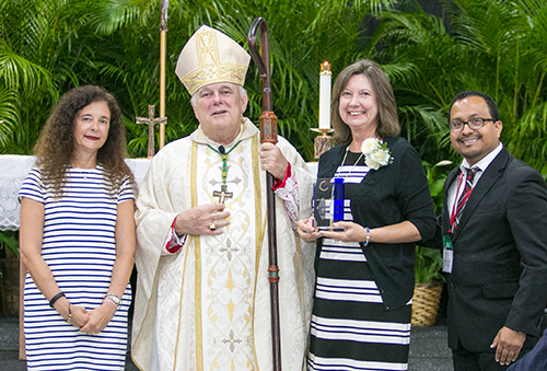 Accompanied by Superintendent of Schools Kim Pryzbylski, left, and Office of Catechesis Director Peter Ductram, Archbishop Thomas Wenski gives a 2016 Catechetical Leadership Award to Maryann Hotchkiss, director of religious education at St. Maximilian Kolbe Parish in Pembroke Pines.